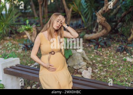 Une femme enceinte éprouve un moment d'inconfort, aux prises avec un mal de tête pendant la grossesse, soulignant le défi commun et la nécessité de Banque D'Images