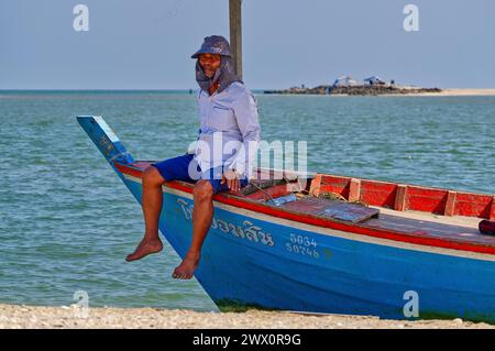 Pêcheur reposant sur un bateau bleu et rouge a atterri sur une broche de sable dans le golfe de Thaïlande Banque D'Images