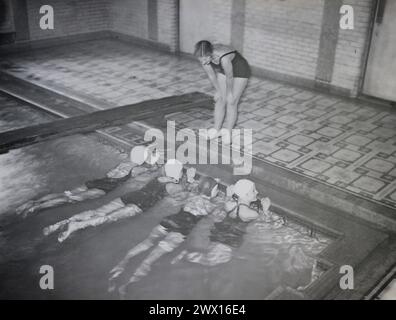 Cette photographie représente une jeune femme affiliée à la National Youth Administration alors qu'elle enseigne une leçon de natation au YWCA à Middletown, Connecticut CA. 1935-1942 Banque D'Images