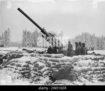 Légende originale : équipage de canon de la «Black Widow», canon anti-aérien de 90 mm creusé à l'extérieur de Bastogne, Belgique, sur le point de tirer sur un avion ennemi aperçu dans la région. Batterie B 217ème Bn (radar) Bastogne. env. 1945 Banque D'Images