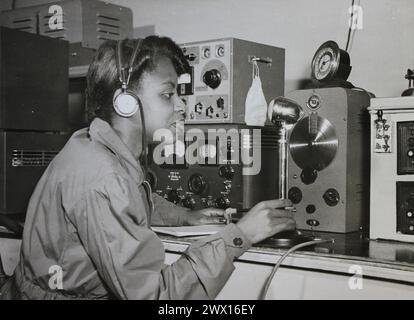 Cette photographie représente une jeune femme alors qu'elle teste les réparations faites à une radio lors d'un atelier de l'Administration nationale de la jeunesse CA. 1939-1943 Banque D'Images