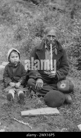 Sisseton-Wahpeton Oyate de la réserve Lake traverse, Dakota du Sud : homme amérindien âgé, John Bear, fumant une pipe avec un enfant assis à côté de lui CA. 1937 Banque D'Images