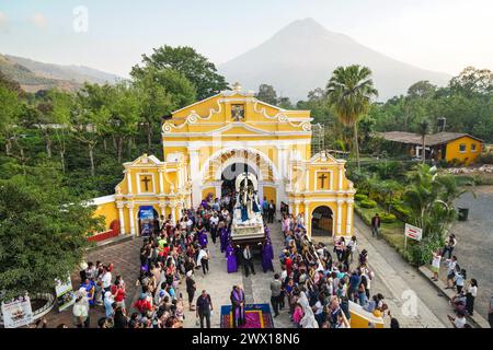 Antigua, Guatemala. 26 mars 2024. Les pénitents catholiques transportent le flotteur processionnel du Jésus de Nazareth hors de l'Ermita de El Calvario avec le volcan Agua se levant derrière, le 26 mars 2024 à Antigua, au Guatemala. Les processions opulentes, les algèbres détaillées et les traditions séculaires attirent plus d'un million de personnes dans l'ancienne capitale. Crédit : Richard Ellis/Richard Ellis/Alamy Live News Banque D'Images