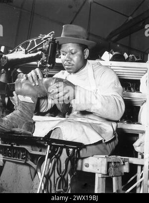 Howard Wilson utilise la machine à coudre dans le C. & E. Shoe Shop à Fort Benning, en Géorgie, alors qu'il termine une paire de bottes de parachutistes CA. Juillet 1942 Banque D'Images