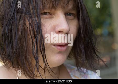 Gros plan sur le visage d'une femme aux cheveux courts mouillés dans la nature Banque D'Images