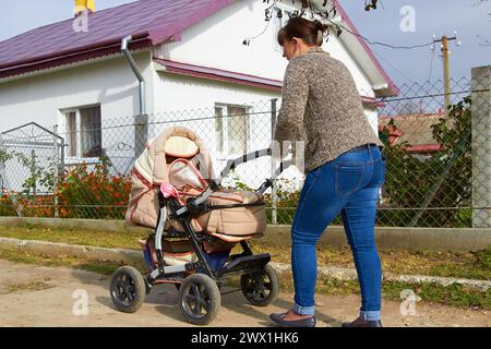 femme rentre chez elle après une promenade avec une poussette Banque D'Images