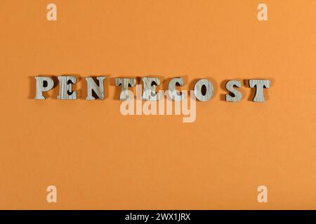 Le mot Pentecost est composé de lettres en bois sur fond orange Banque D'Images
