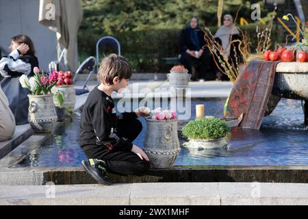 Téhéran, Iran. 26 mars 2024. Un garçon regarde des œufs colorés exposés pour le Nowruz, le nouvel an iranien, devant le Palais Niavaran dans le Nord de Téhéran, capitale de l'Iran, le 26 mars 2024. Les gens ont visité le Palais Niavaran pendant les vacances du nouvel an de Nowruz, qui tombe le 20 mars de cette année. Crédit : Shadati/Xinhua/Alamy Live News Banque D'Images