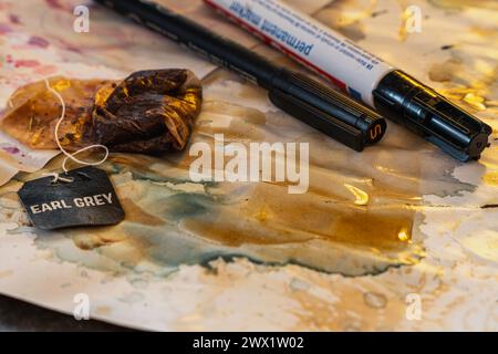 Angle élevé de sac à thé utilisé avec fil se connectant à l'étiquette noire avec les lettres earl Grey tout en étalant l'eau de thé sur la feuille salissante avec des taches de couleur et marque Banque D'Images