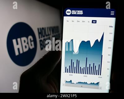 Personne tenant smartphone avec la page Web de la société de bowling britannique Hollywood Bowl Group plc devant le logo. Concentrez-vous sur le centre de l'écran du téléphone. Banque D'Images