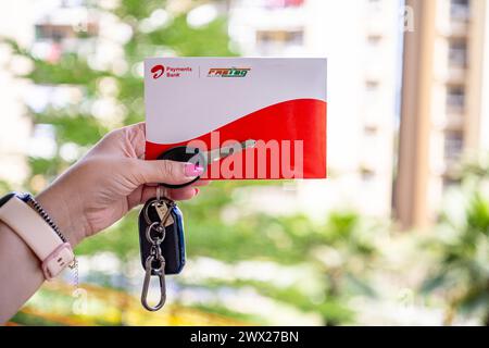 Femme tenant Airtel Payment Bank Fastag avec la clé de voiture montrant la nouvelle méthode de paiement de NHAI autorité routière nationale de l'Inde pour Toll Banque D'Images