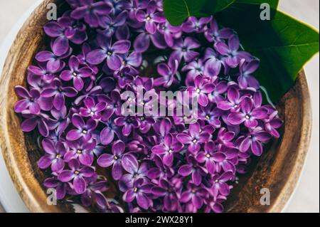 Spa et composition de bien-être avec de l'eau de fleurs de lilas parfumées dans un bol en bois sur fond de marbre. Aromathérapie, vue de dessus. Banque D'Images