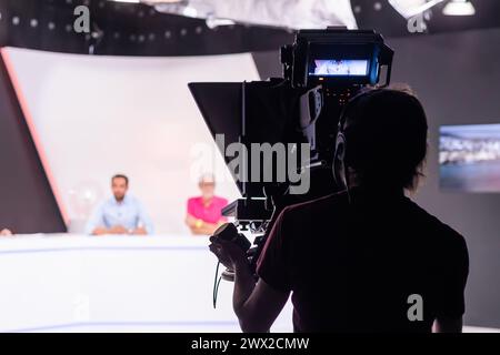 Silhouette de caméraman. Cameraman professionnel - couverture de l'événement avec une vidéo, silhouette de cameraman sur les actualités en studio en direct. Diffusion télévisée en direct Banque D'Images
