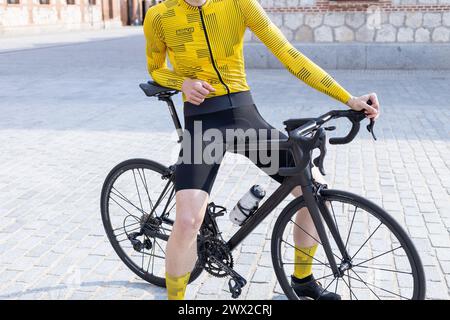 vue de face d'un cycliste méconnaissable en maillot jaune reposant sur son vélo Banque D'Images