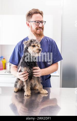 Vétérinaire masculin posant avec son chiot patient Banque D'Images