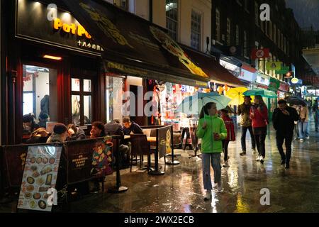 Météo britannique, Londres, 26 février 2024 : un temps froid et pluvieux revient en Angleterre les rues du quartier chinois de Soho reflètent les lumières et les gens se réfugient sous leurs parapluies. Crédit : Anna Watson/Alamy Live News Banque D'Images