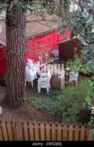 Chaises en plastique blanc empilées à côté d'un bâtiment en bois rouge Banque D'Images