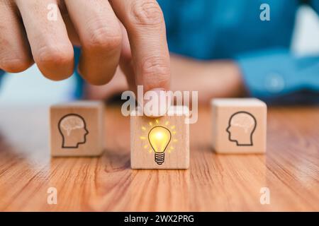 brainstorming idée créative et innovation. Main mettant sur le bloc de cube en bois avec l'icône d'ampoule sur beaucoup de personnes ensemble ayant une idée symbolisée Banque D'Images