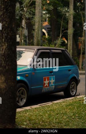 Une voiture bleue avec un autocollant Tamiya était garée derrière un tronc d'arbre avec un style ancien Banque D'Images