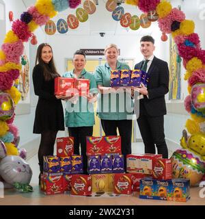 Gloucester, Royaume-Uni. 27 mars 2023. Le Property Centre, un agent immobilier avec des succursales situées à Gloucester, Cheltenham, Stroud et Worcester, a fait don de 52 œufs de Pâques au Centre pour enfants du Gloucestershire Royal Hospital, un pour chaque lit de l'unité. Josh Richards, directeur principal de la succursale du Property Centre - Churchdown (à droite) et Jenna Cebryk, directrice des médias sociaux du Property Centre (à gauche) avec Michelle Wallace et Natalie Hill, spécialistes du jeu au Gloucestershire Royal Hospital. Crédit : Carl Hewlett/Alamy Live News Banque D'Images