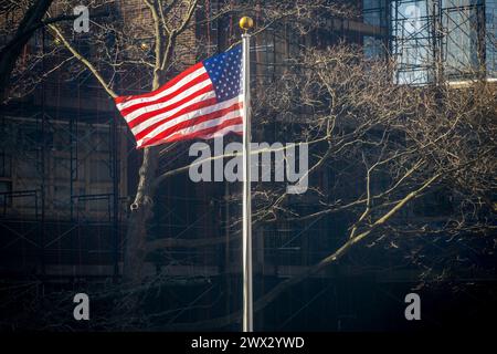 Un drapeau américain est fouetté par le vent à l'extérieur d'une école dans le quartier de Chelsea à New York le mardi 12 mars 2024(© Richard B. Levine) Banque D'Images