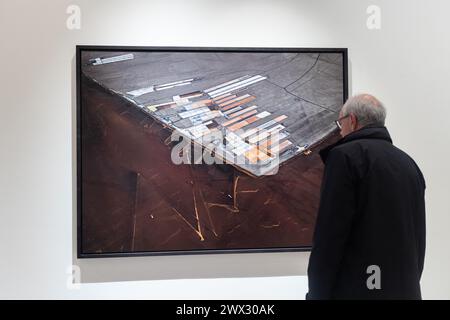 Londres, Royaume-Uni. 26 mars 2024. Un homme regarde de plus près une grande impression de l'artiste photographe Edward Burtynsky à la Saatchi Gallery, Londres. Il fait partie de l'exposition extraction / abstraction qui est la plus grande exposition jamais montée dans la carrière de plus de 40 ans du photographe de renommée mondiale. Crédit : Katie Collins/EMPICS/Alamy Live News USAGE ÉDITORIAL UNIQUEMENT Banque D'Images