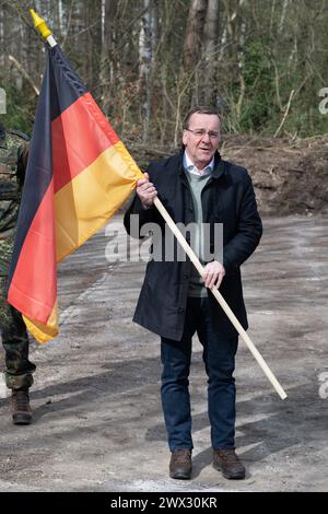 Bernsdorf, Allemagne. 27 mars 2024. Boris Pistorius (SPD), ministre fédéral de la Défense, tient un drapeau allemand sur le site d'une base prévue de la Bundeswehr. Le nouveau bataillon logistique 471 sera stationné sur le site de Bernsdorf-Straßgräbchen. Crédit : Sebastian Kahnert/dpa/Alamy Live News Banque D'Images