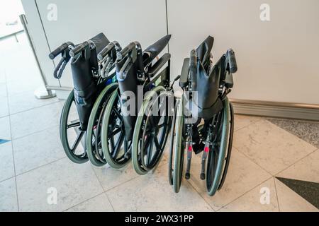 Fauteuil roulant pliant pour les personnes ayant des besoins spéciaux ou des handicaps dans un bâtiment de transport public aéroports gares hôpitaux. Banque D'Images