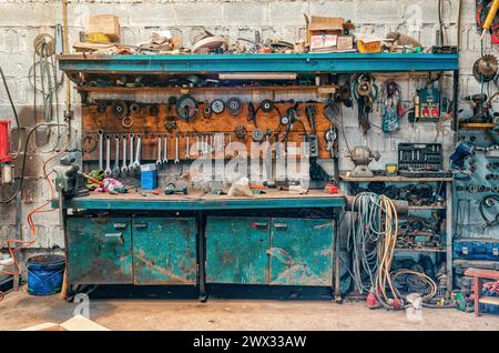 Atelier vintage. Des outils antiques accrochent au mur, réparer l'équipement sur la table. Vue de face Banque D'Images