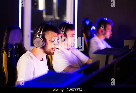 Équipe de joueurs jouant au jeu vidéo sur PC au cyber club pendant le championnat E-sport, rack Focus des ordinateurs aux joueurs dans le casque, tournoi sportif. Banque D'Images