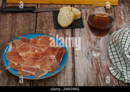 Assiette de jambon ibérique nourri aux glands espagnols au premier plan avec du pain et du vin apéritif typiquement espagnol Banque D'Images