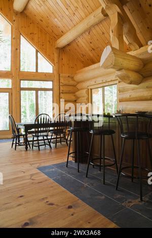 Îlot avec comptoir en granit gris foncé et tabourets de bar en bois teinté noir, table ancienne avec chaises hautes arrondies dans la cuisine ouverte Banque D'Images