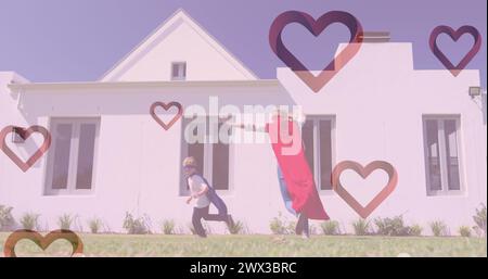 Image de cœurs tombant sur une femme caucasienne et son fils jouant ensemble dans le jardin. image générée numériquement par le concept de mode et de style de vie. Banque D'Images