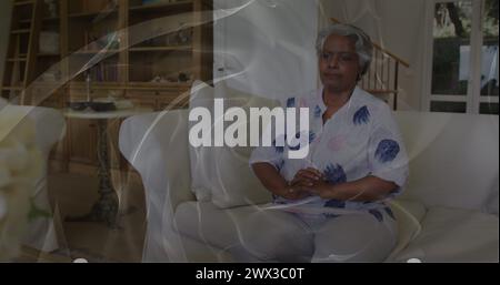 Image de formes en mouvement sur une triste femme afro-américaine senior. semaine de sensibilisation à la santé mentale et concept de célébration image générée numériquement. Banque D'Images