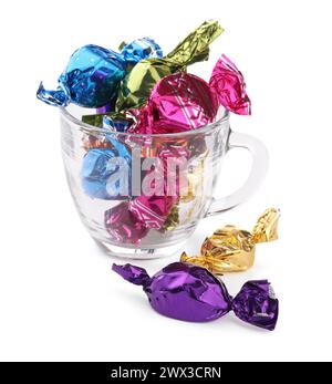 Tasse en verre avec des bonbons dans des emballages colorés isolés sur blanc Banque D'Images