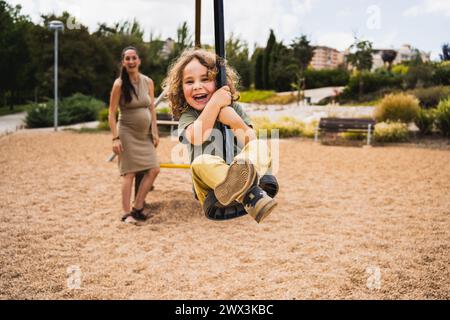 portrait de petit garçon heureux jouant avec tyrolienne dans l'aire de jeux Banque D'Images