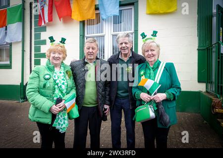 Deux femmes portant Happy St Patrick's Day boppers avec leurs maris devant Warrington Irish Club Banque D'Images