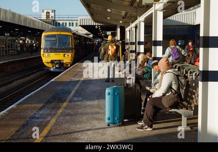 Les passagers avec des valises en attente comme train du Sud-Ouest, SWR, arrivent à Southampton Railway Station Platform un matin d'hiver froid, Royaume-Uni Banque D'Images