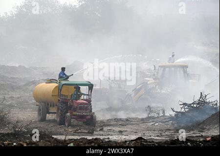 Noida, Inde. 27 mars 2024. NOIDA, INDE - MARS 27 : les pompiers tentent d'éteindre un incendie dans un dépôt de déchets horticoles dans le secteur 32 le 27 mars 2024 à Noida, en Inde. Le feu a commencé vers 18 heures lundi et a englouti une zone d'environ 1,5 km de large et 2 km de long dans le secteur 32, a déclaré le chef des pompiers de GB Nagar. Tous les déchets horticoles de partout à Noida sont déversés sur cette parcelle pour être convertis en compost. (Photo de Sunil Ghosh/Hindustan Times/Sipa USA) crédit : Sipa USA/Alamy Live News Banque D'Images