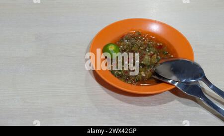 Une assiette de sauce avec condiment à la sauce Chili soja, avec un calamansi sur le côté, et une paire de fourchette en métal et une cuillère. Avec espace de copie sur la gauche. Banque D'Images