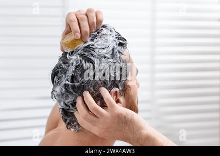 Homme se lavant les cheveux avec une barre de shampooing solide dans la salle de bain, gros plan Banque D'Images