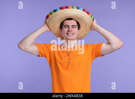 Jeune homme dans le chapeau sombrero mexicain sur fond violet Banque D'Images