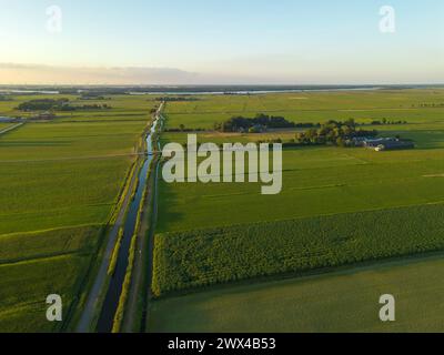 Vue en angle élevé des champs agricoles, des canaux d'eau et du parc de moulins à vent sur fond. Banque D'Images