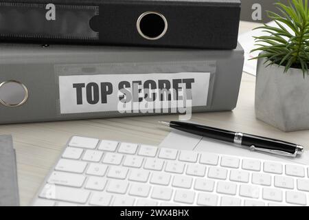 Tampon Top secret. Dossiers, clavier d'ordinateur, stylo et plante d'intérieur sur la table en bois blanc, gros plan Banque D'Images