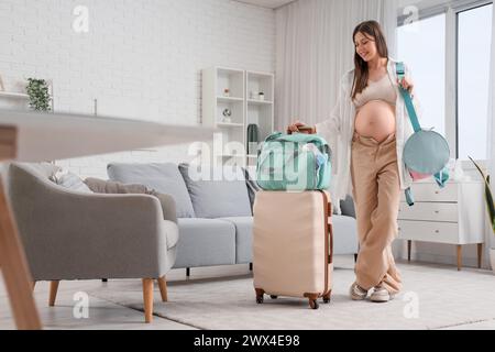 Jeune femme enceinte avec sacs d'hôpital de maternité emballés à la maison Banque D'Images