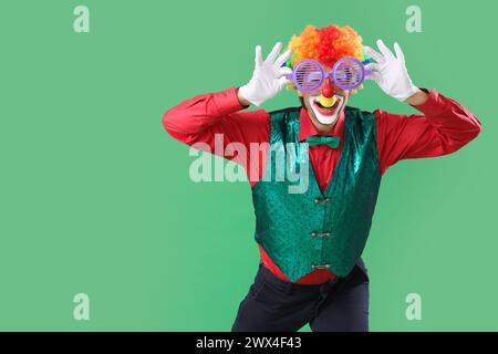 Portrait de clown avec des lunettes de nouveauté sur fond vert. Fête du fou d'avril Banque D'Images