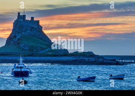 Une vue à l'aube du château de Lindisfarne vue depuis le port avec des bateaux amarrés au premier plan sur Holy Island dans le Northumberland Banque D'Images