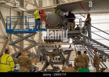 Boeing Contractors et Airman du 22nd maintenance Group attachent un Wing Aerial ravitaillement Pod (WARP) sur un KC-46A Pegasus le 5 mars 2024 à McConnell Air Force base, Kansas. Les Warps sont une fonctionnalité optionnelle qui a été incluse dans la conception originale du KC-46 et les certifications sont en cours d'élaboration depuis 2019. Les Warps sont montés sur les ailes de l’avion et permettent au KC-46 de ravitailler deux avions simultanément. (Photo de l'US Air Force par Airman 1st Class Gavin Hameed) Banque D'Images