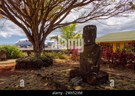 Île de Pâques, Chili. 31 décembre 2023. Un avion LATAM sur le tarmac de l'aéroport international de Mataveri derrière un moai sculpté par Manuel Tuki. Banque D'Images