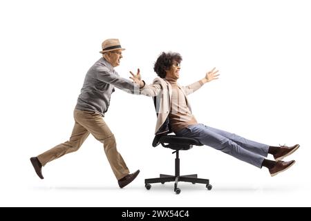 Homme âgé courant et poussant jeune homme assis dans une chaise de bureau isolé sur fond blanc Banque D'Images